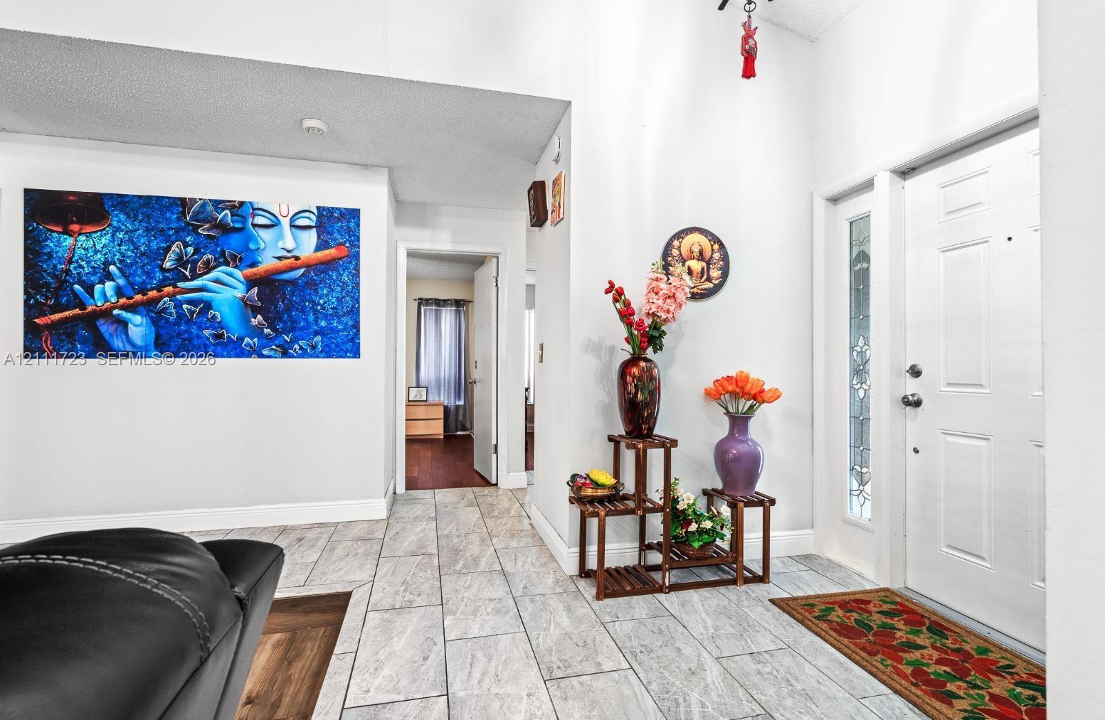 Foyer featuring light-toned stone-finish tile flooring and an entry door with decorative glass side-lite