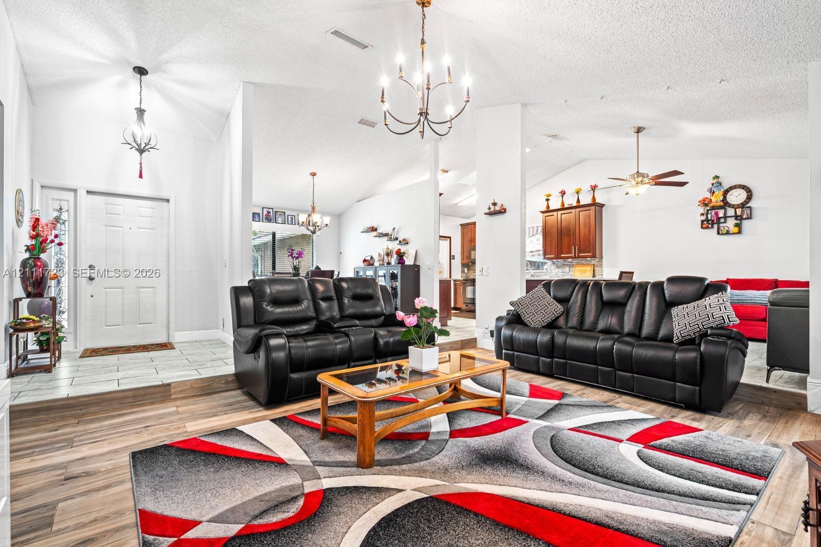 Vaulted ceilings with exposed metal chandeliers, wood-finish flooring, and a multi-level floor plan featuring decorative tile accents