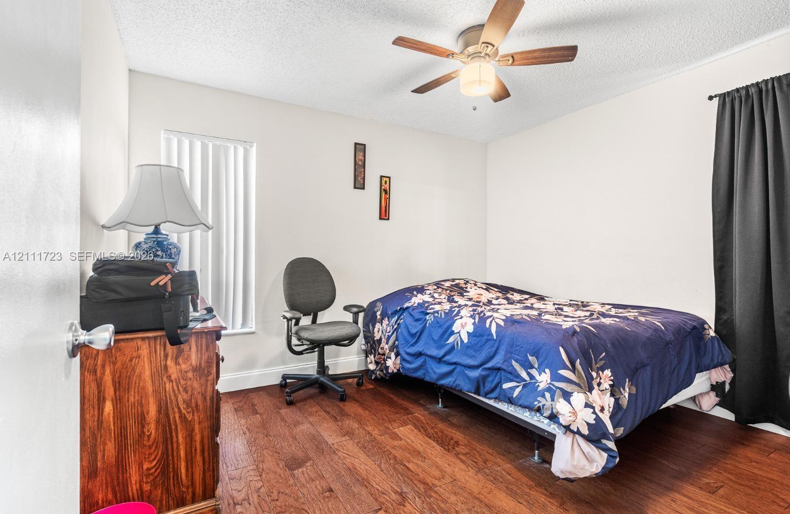 Interior room featuring wood-finish flooring, a ceiling fan with integrated lighting, and vertical window blinds