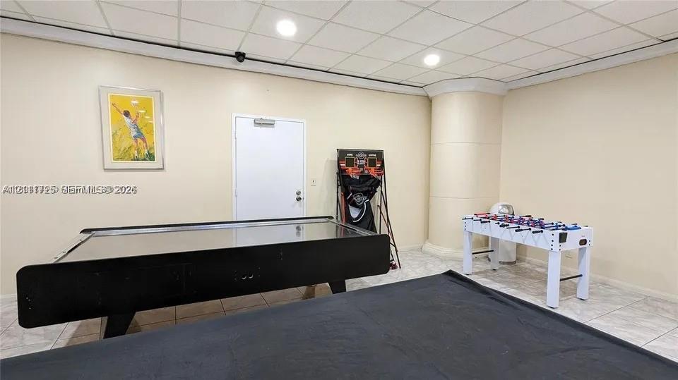 Interior space featuring neutral wall tones, tile flooring, recessed ceiling lighting, and a drop ceiling system