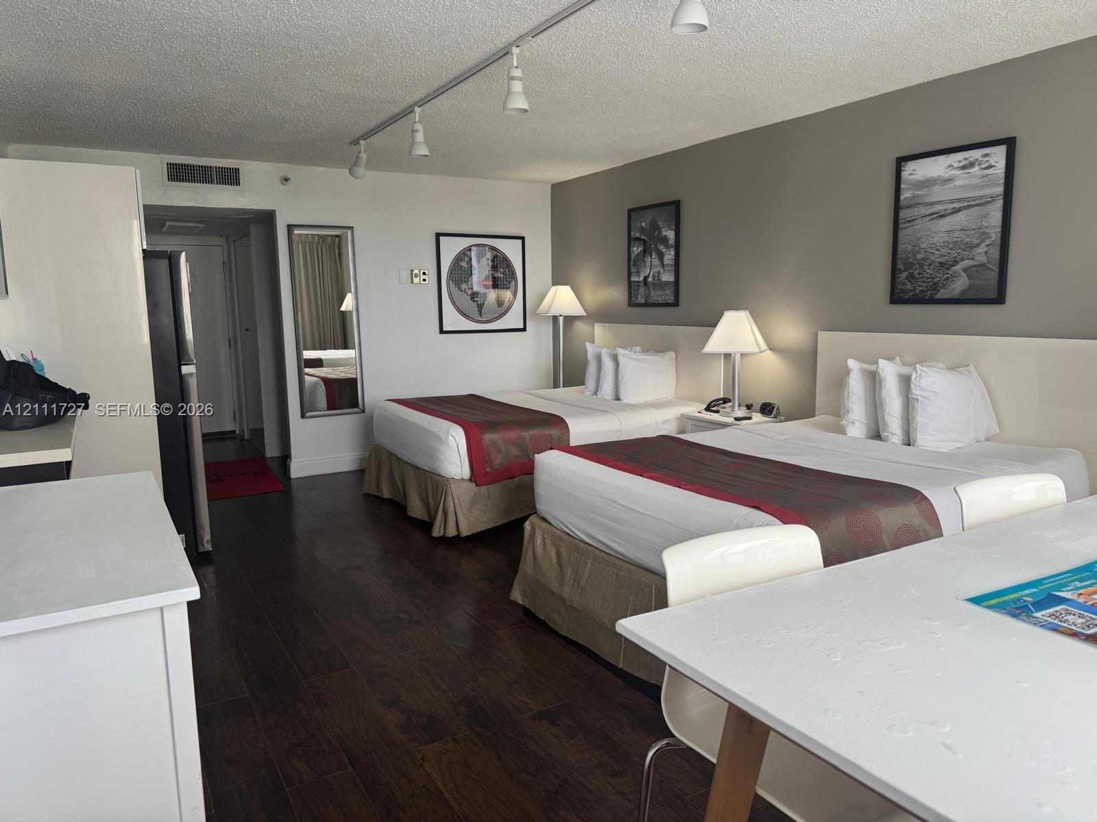 Spacious room featuring wood-finish flooring, track lighting, and a neutral color palette Spacious room featuring wood-finish flooring, track lighting, and a neutral color palette