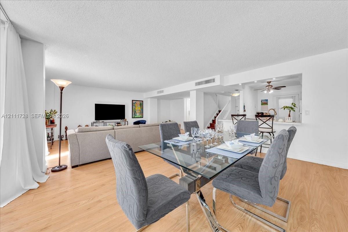 Open-concept interior featuring light wood-finish flooring, a pass-through kitchen window, and a built-in staircase