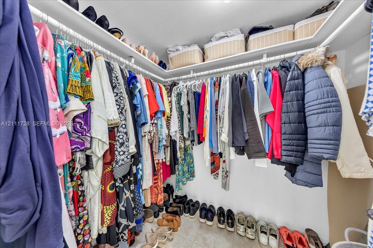 Walk-in closet featuring multi-level white wire shelving and tile flooring