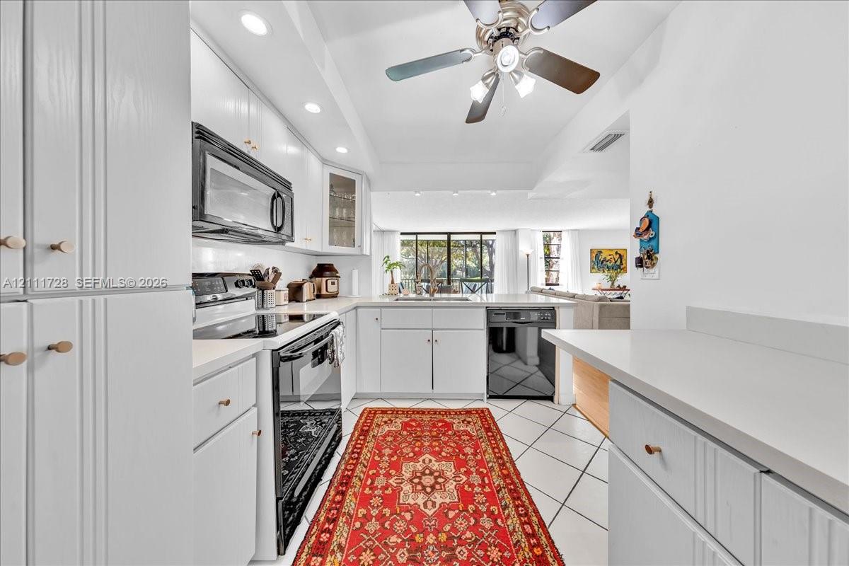 Kitchen featuring white cabinetry, solid surface countertops, recessed lighting, tile flooring, and built-in appliances