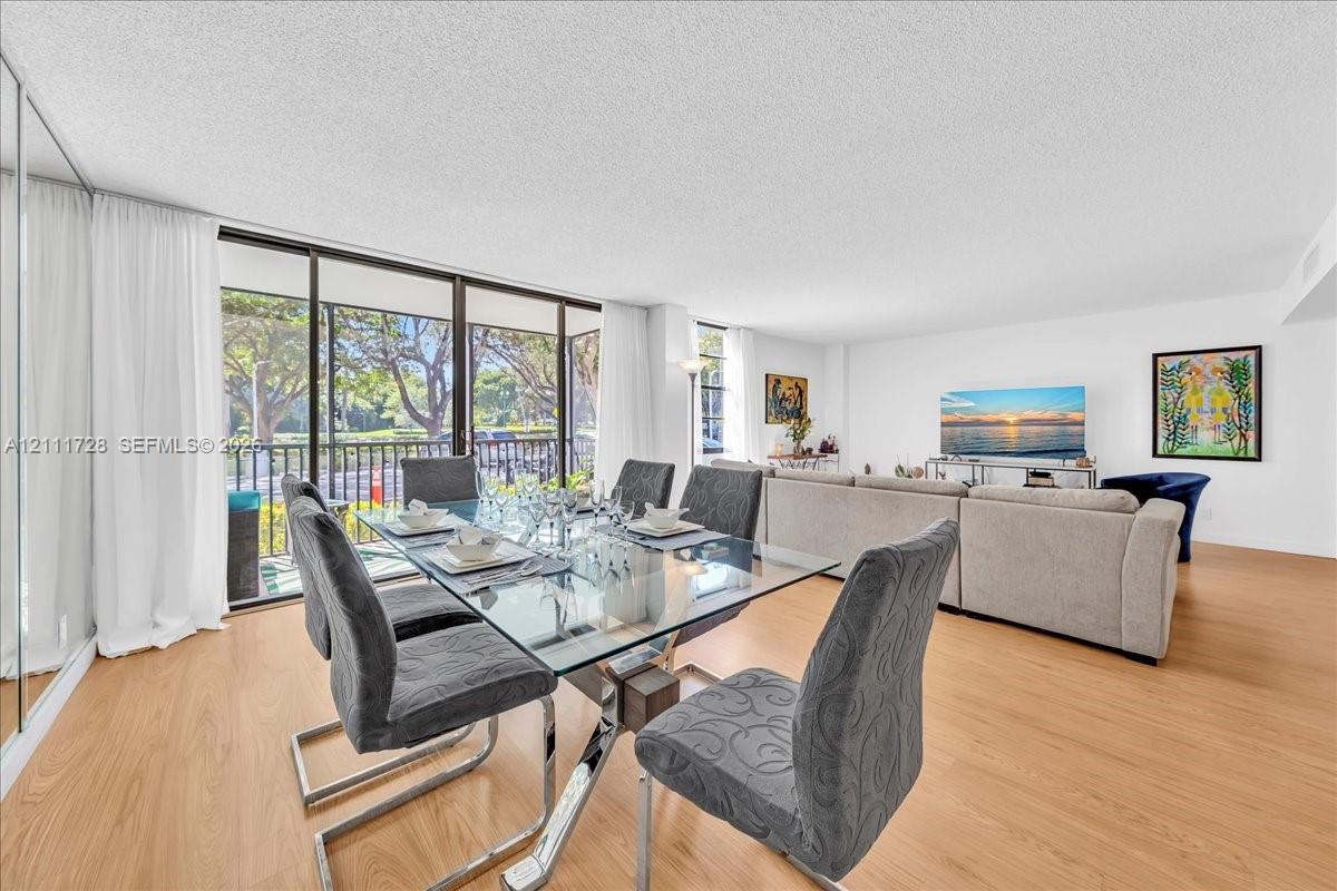Open-concept interior featuring wood-finish flooring, full-height mirrored wall, and expansive sliding glass doors with metal frame balustrade