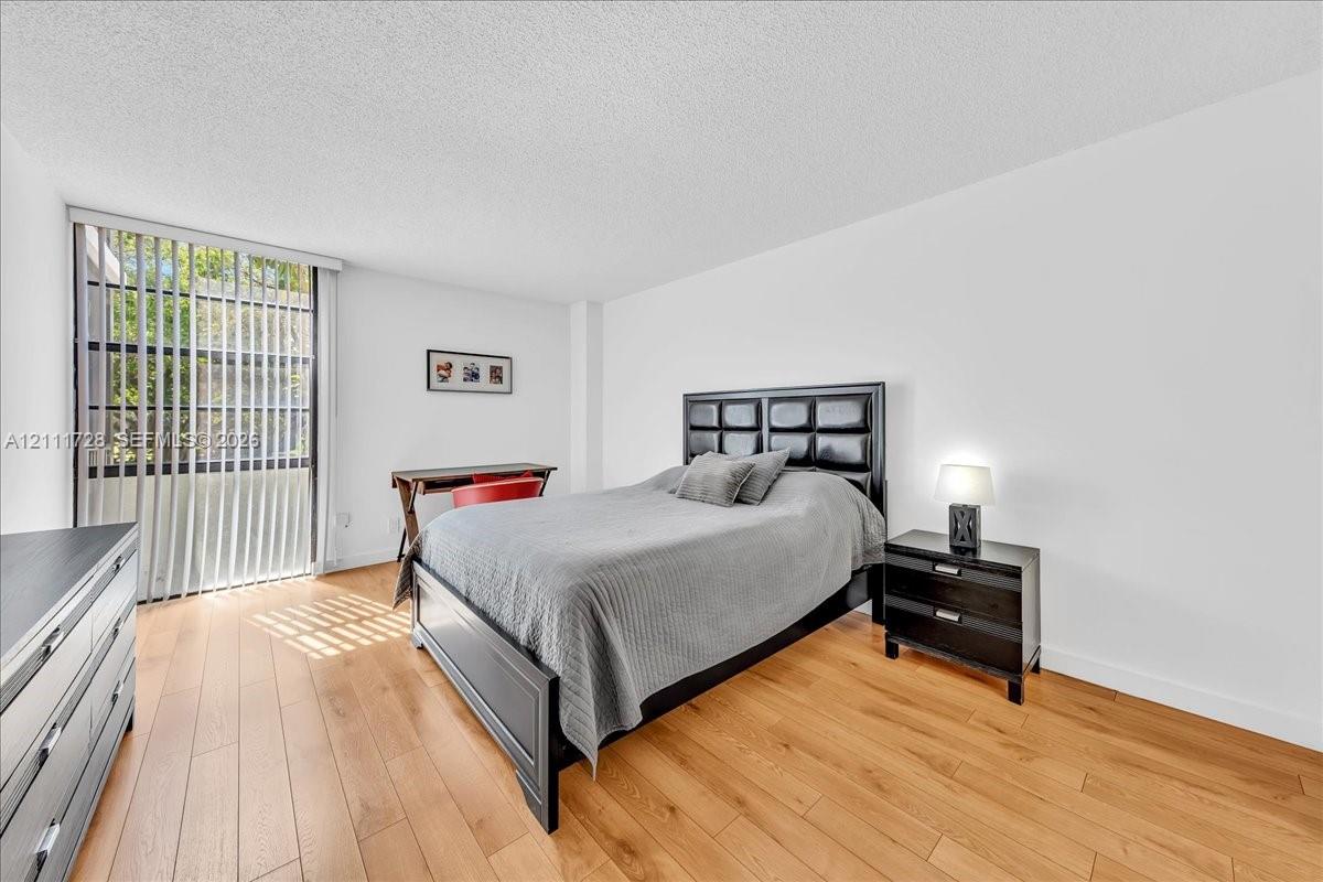 Wood-finish flooring, full-height floor-to-ceiling windows, and vertical window blinds