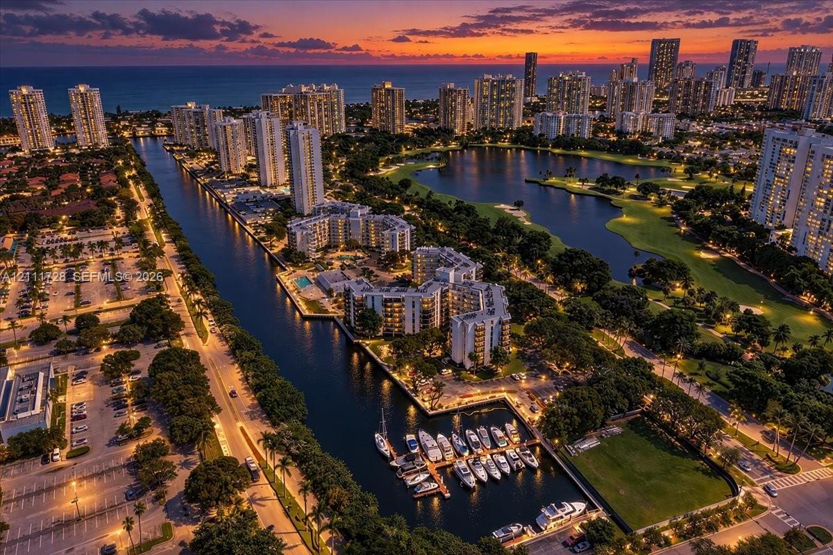 Aerial perspective of a coastal waterfront community featuring deep-water canal access, private boat slips, multi-level residential structures, and landscaped green space Aerial perspective of a coastal waterfront community featuring deep-water canal access, private boat slips, multi-level residential structures, and landscaped green space