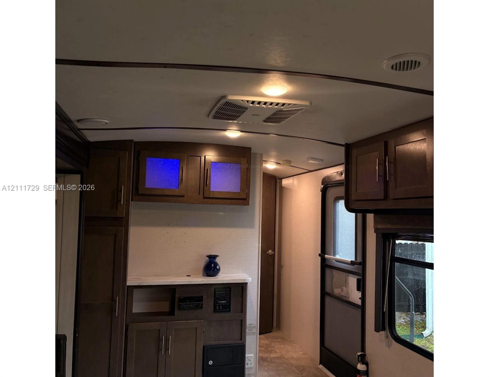 Dark wood-finish cabinetry featuring frosted glass door inserts, built-in lower console with stone-finish countertop, and recessed ceiling lighting