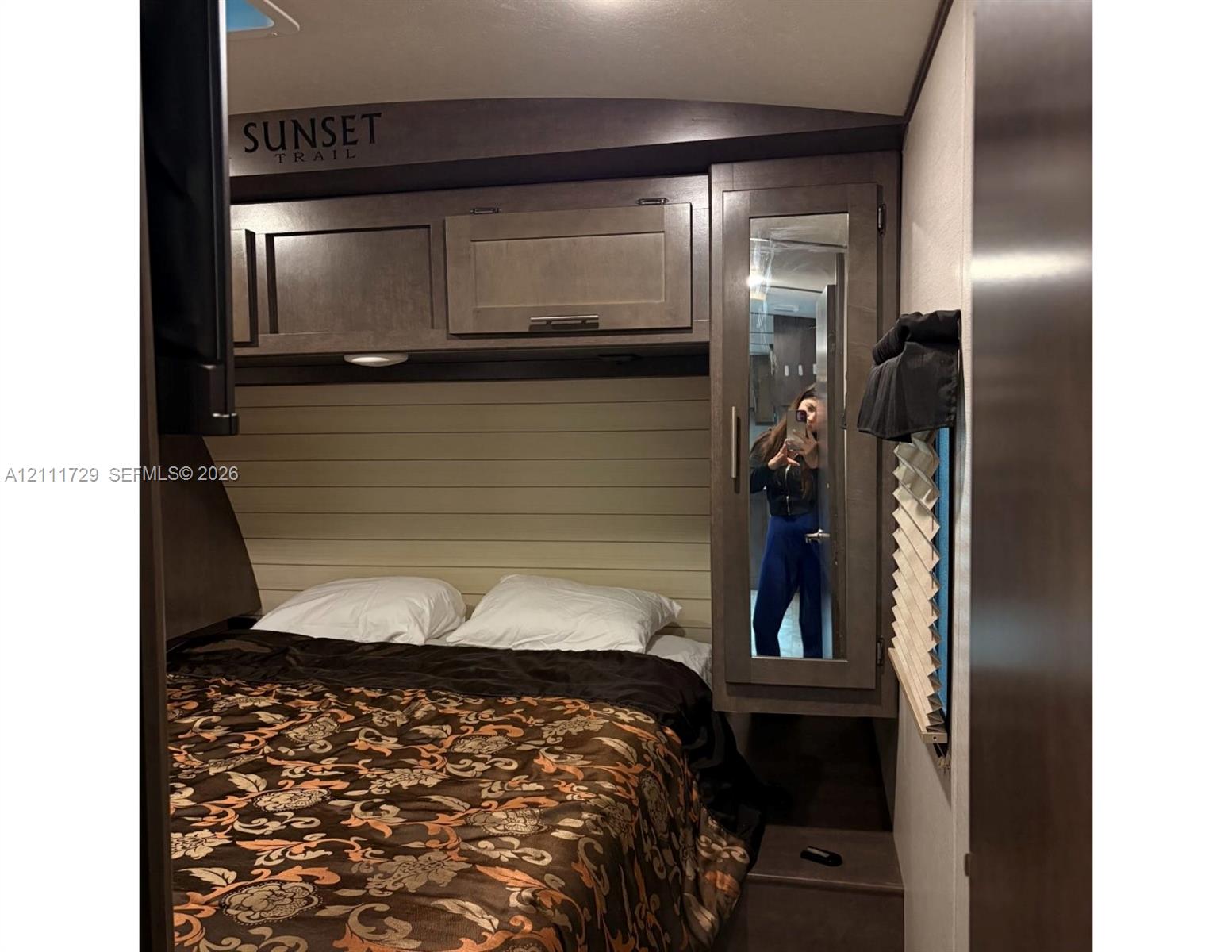 Overhead storage cabinetry, horizontal plank wall accent, and full-length mirrored wardrobe closet
