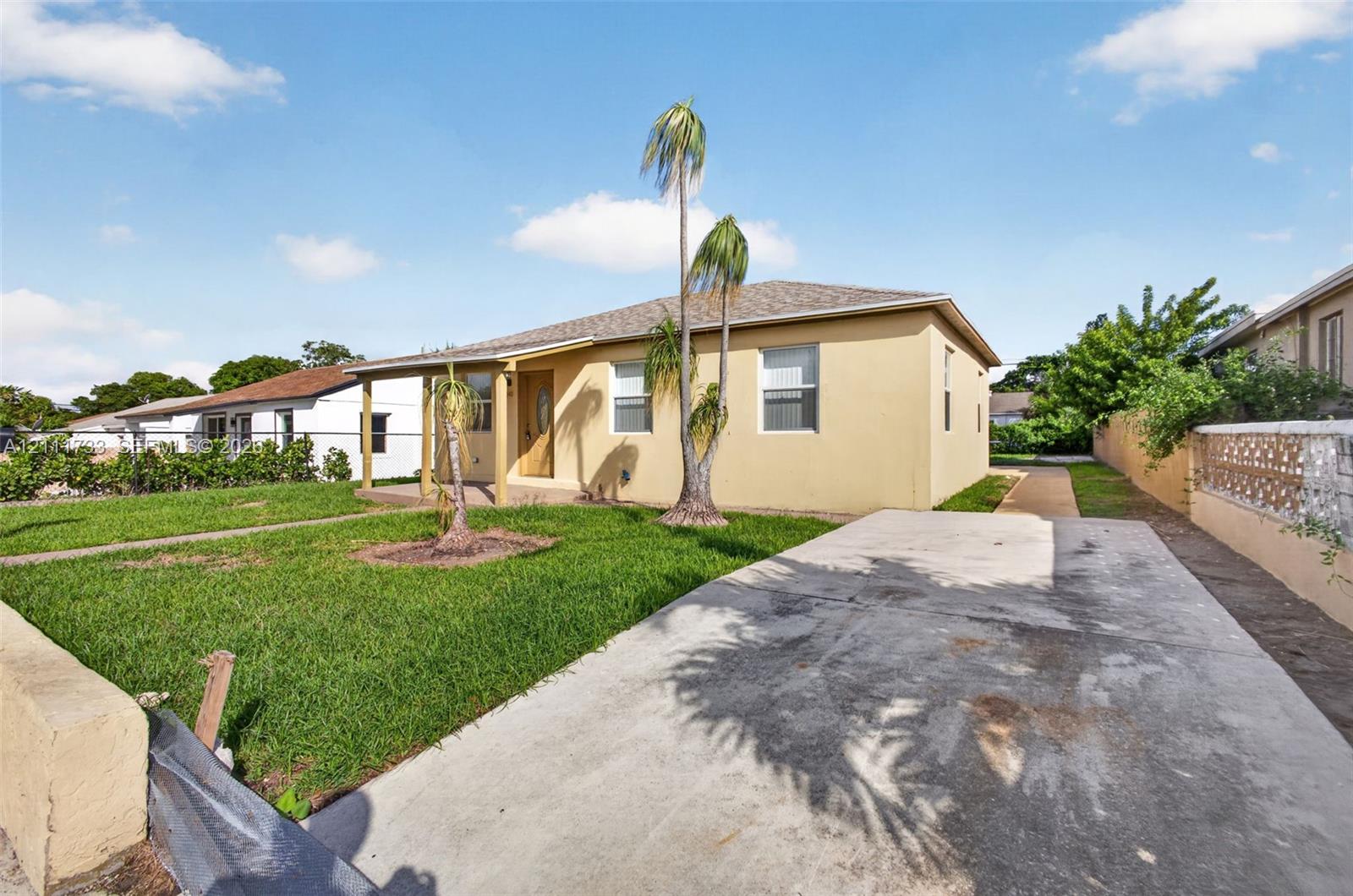 Single-story exterior featuring a concrete driveway, covered entrance, and stucco siding