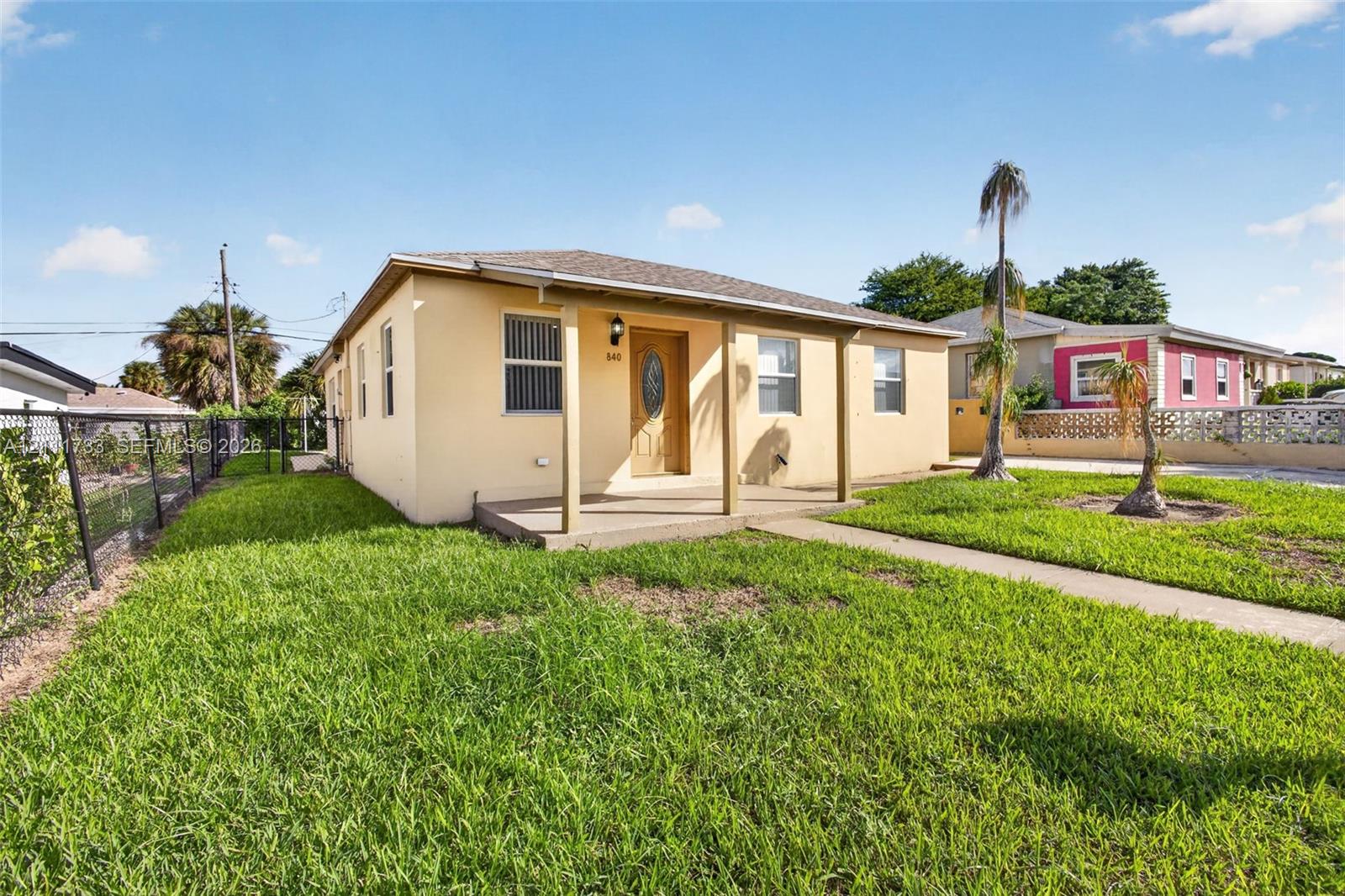 Single-story exterior featuring a stucco facade, covered front porch, asphalt shingle roof, and a concrete walkway