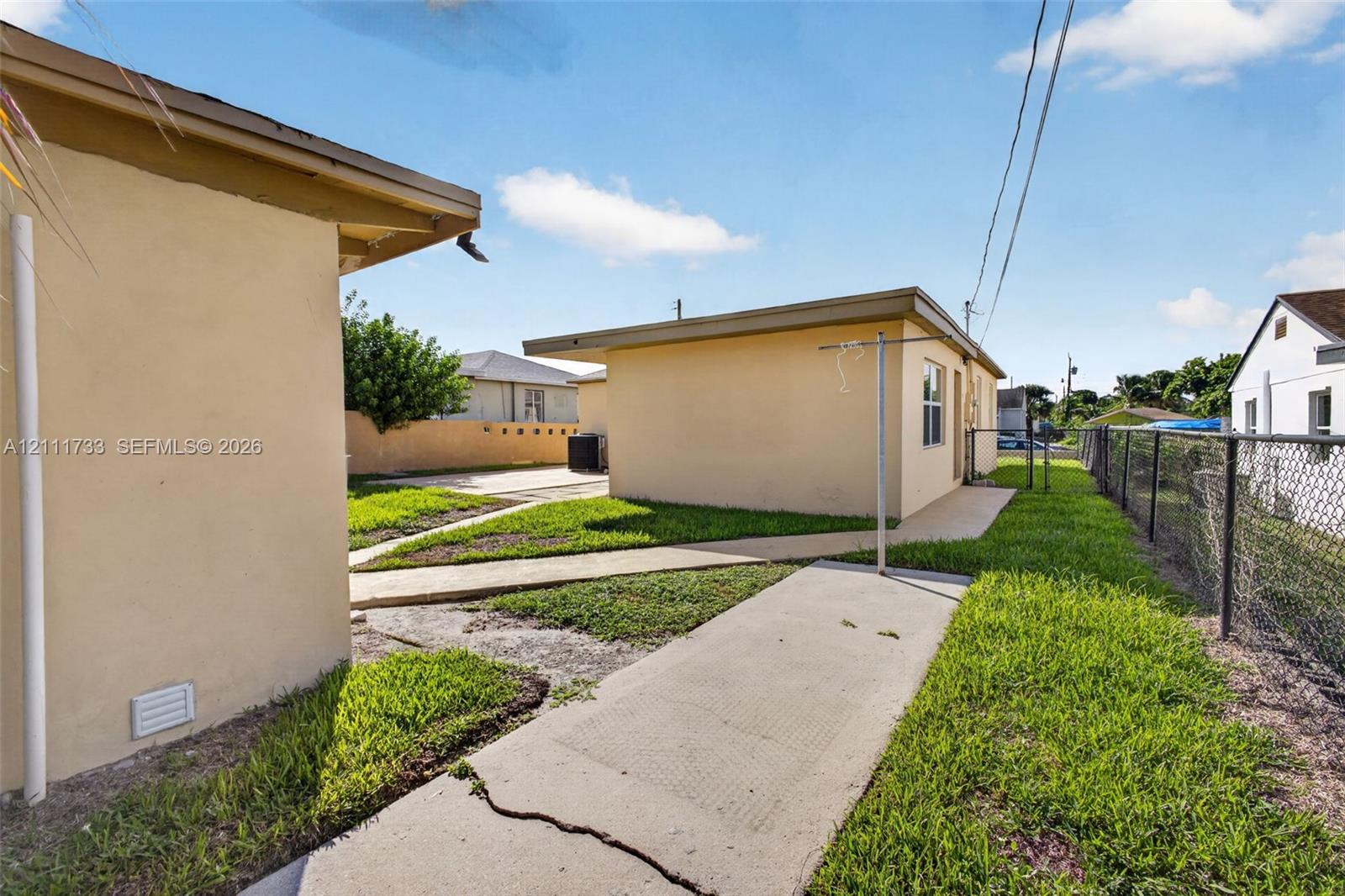 Stucco exterior buildings featuring concrete walkways, grass lawn area, and perimeter chain-link fencing