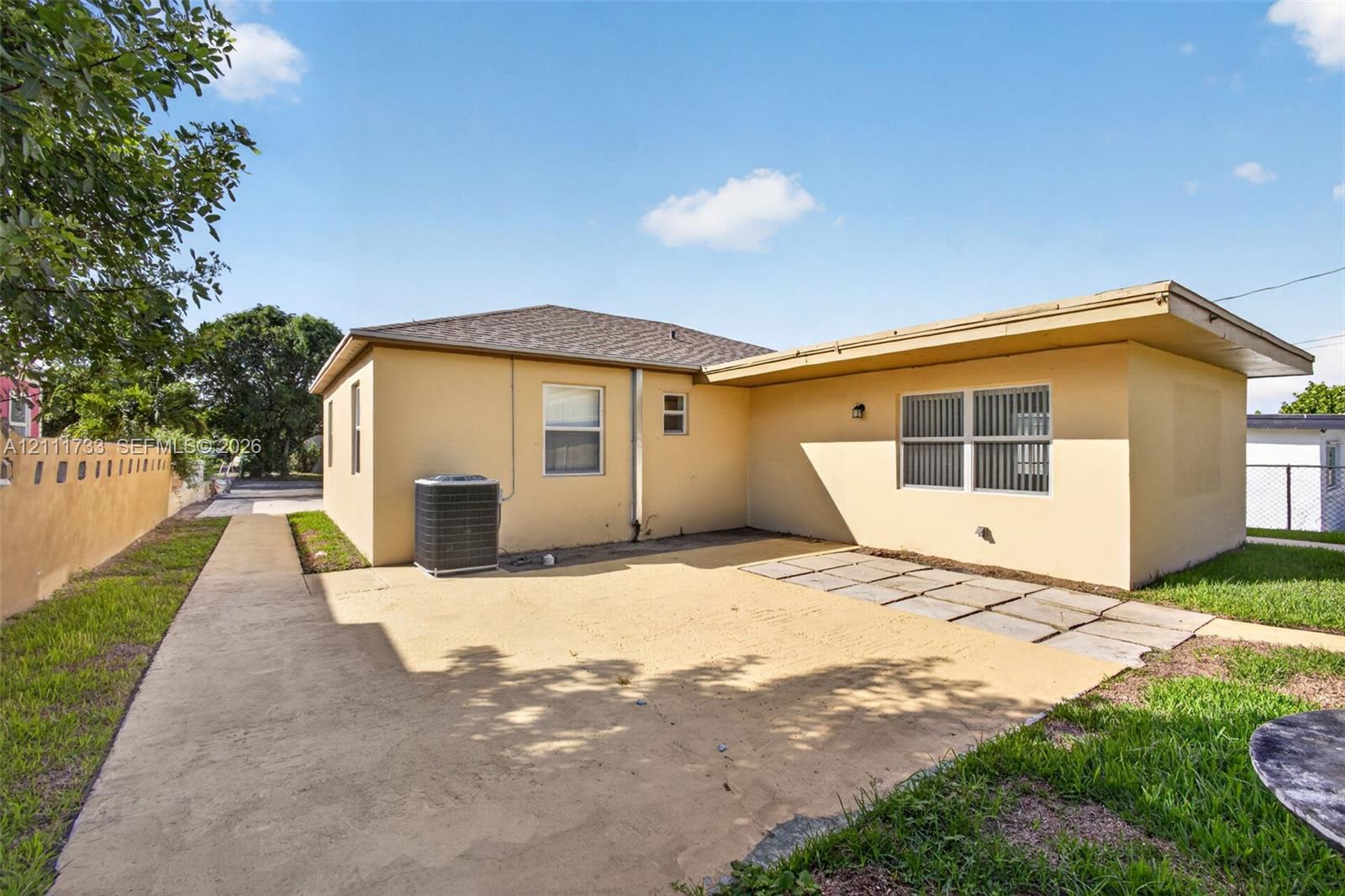 Stucco exterior featuring a concrete patio, stone paver accents, and a masonry perimeter wall