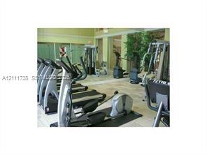 Fitness center featuring tile flooring, mirrored walls, and oversized windows Fitness center featuring tile flooring, mirrored walls, and oversized windows
