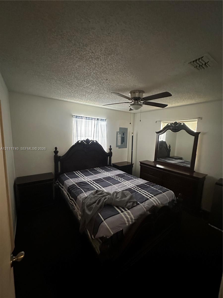 Room featuring dark wall-to-wall carpeting, a central ceiling fan with integrated lighting, and dual windows