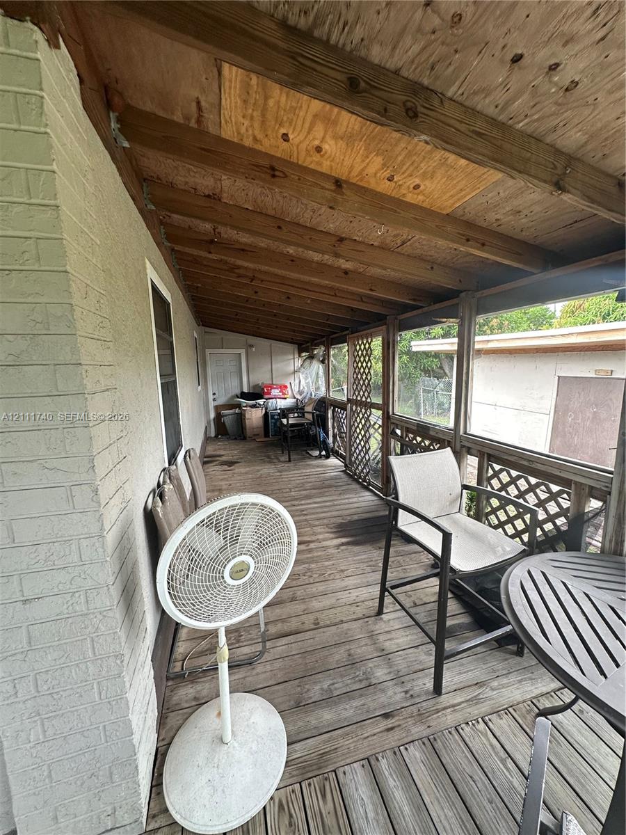 Covered outdoor patio featuring wood decking, exposed timber ceiling beams, and decorative lattice screen walling