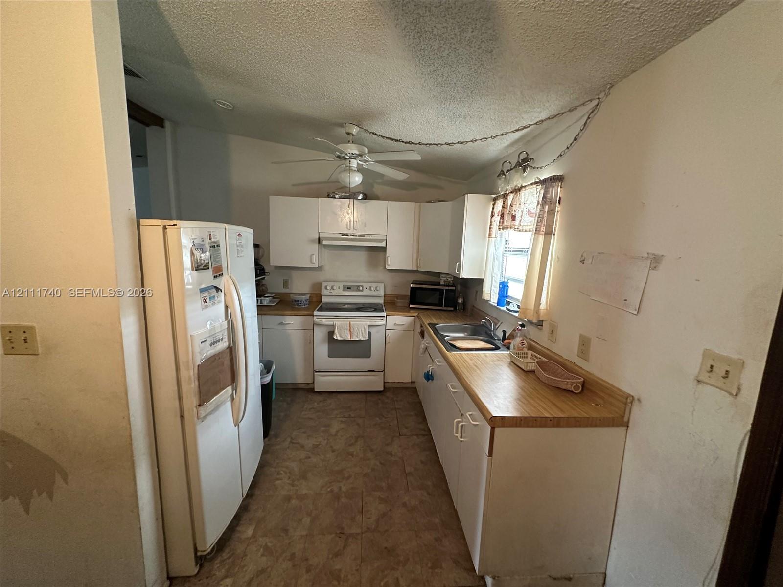 Kitchen featuring white cabinetry, wood-finish countertops, tile flooring, a white electric range, and a ceiling fan