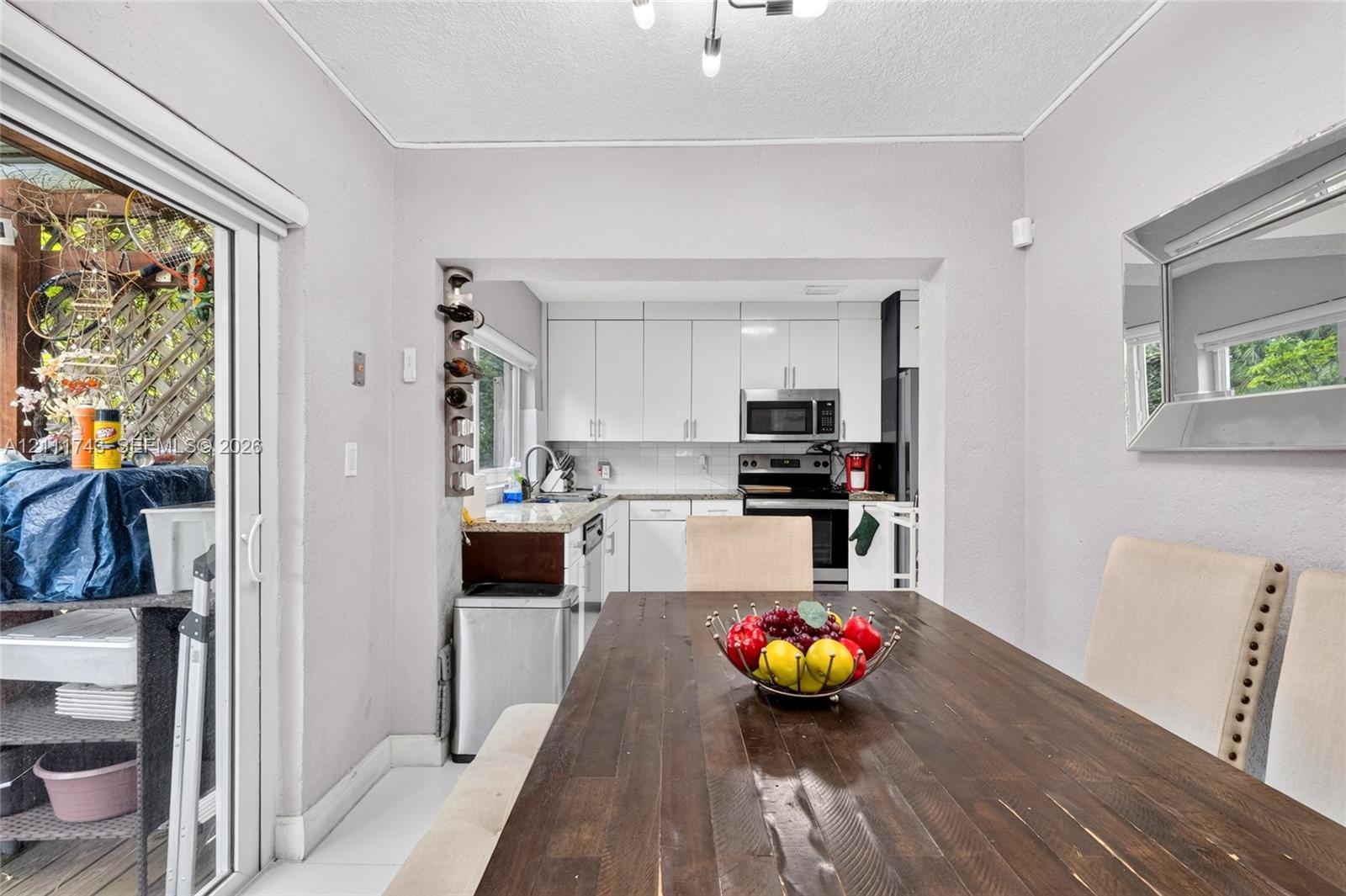 Kitchen featuring white shaker-style cabinetry, stone countertops, and built-in stainless steel appliances, including a microwave and range