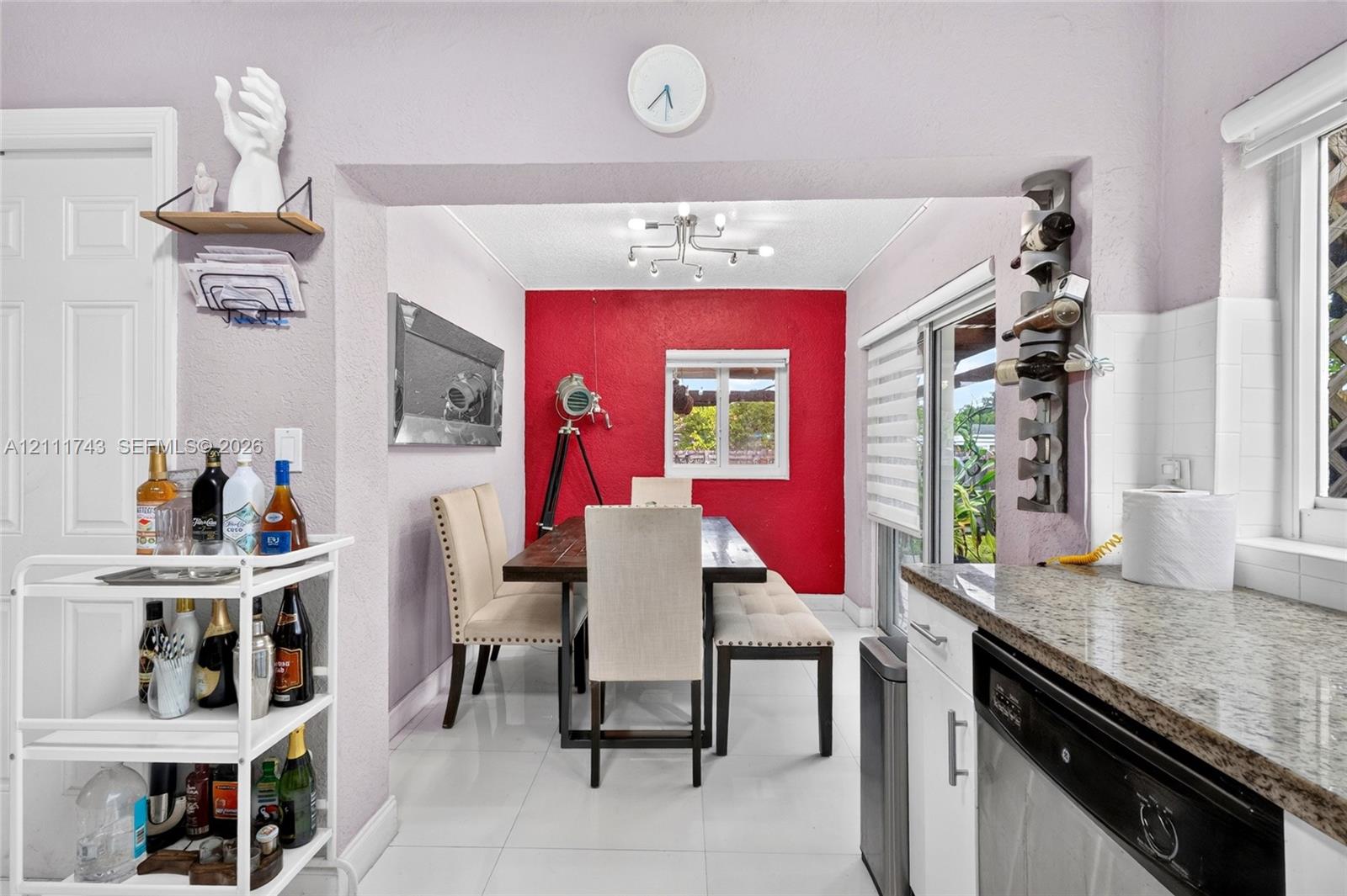 Dining area featuring stone-surfaced kitchen counters, white shaker-style cabinetry, a multi-arm modern light fixture, and sliding glass doors