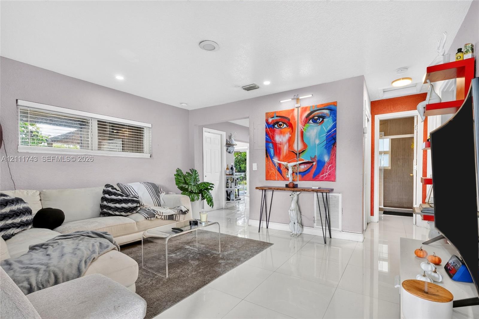 Living area featuring high-gloss tile flooring, recessed lighting, and a horizontal window with blinds