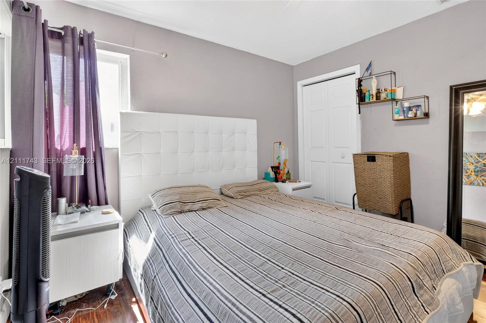 Wood-finish flooring, white bifold closet doors, and wall-mounted shelving
