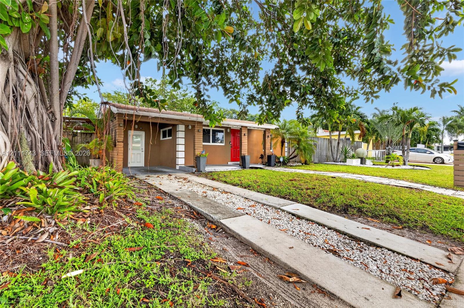 Single-story residence featuring a brick exterior, stone-inlay driveway, covered entrance, and mature landscaping