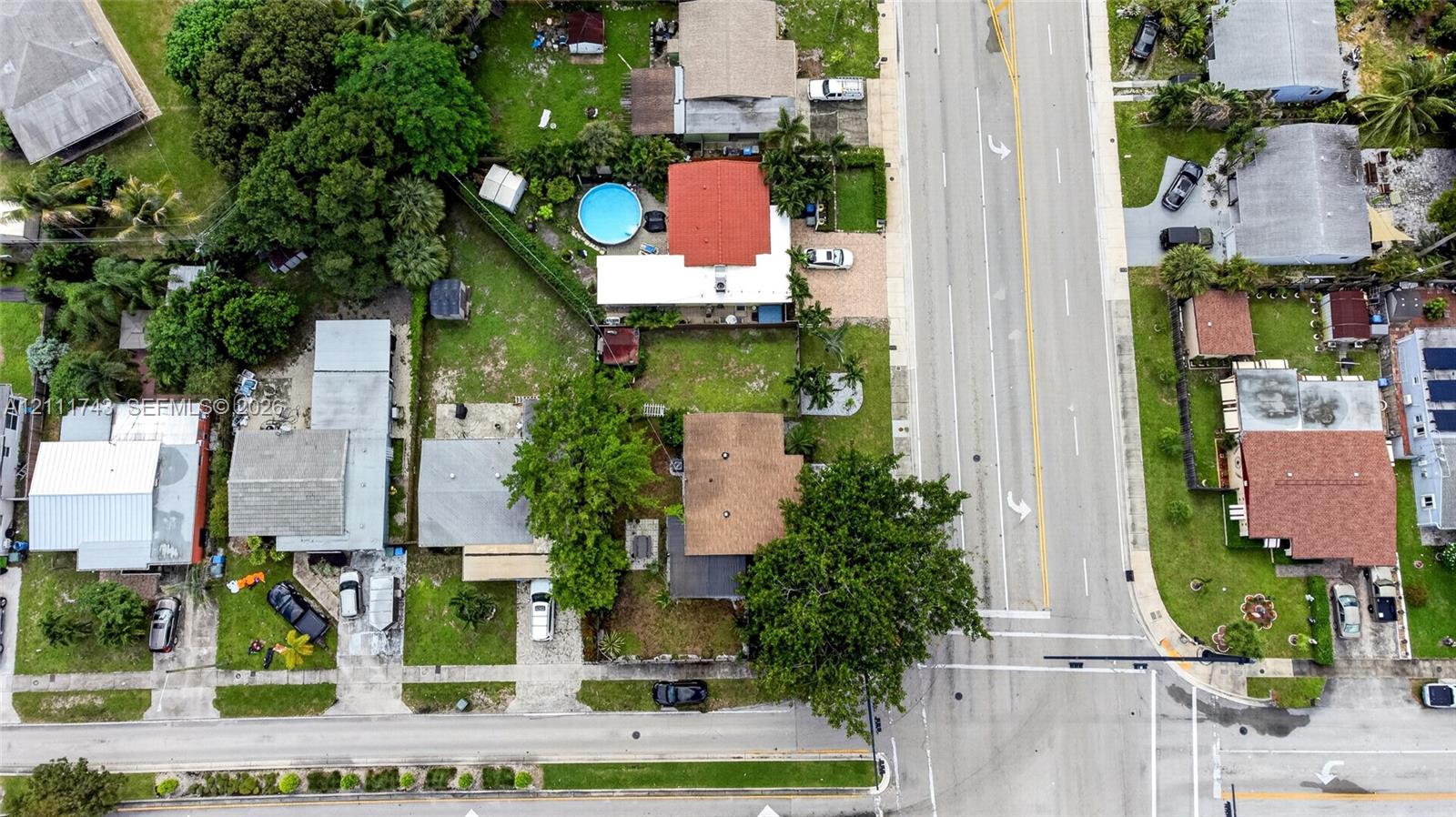Aerial view of the residential property featuring mature trees, landscaped lawns, and paved driveway access