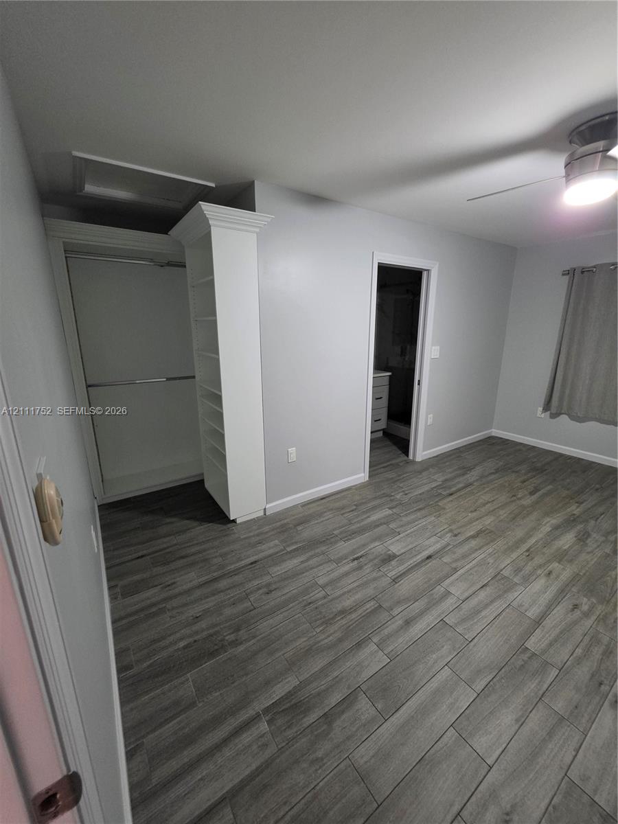 Wood-finish plank flooring, built-in floor-to-ceiling shelving, recessed ceiling fan with integrated lighting, and a closet with a decorative crown molding finish