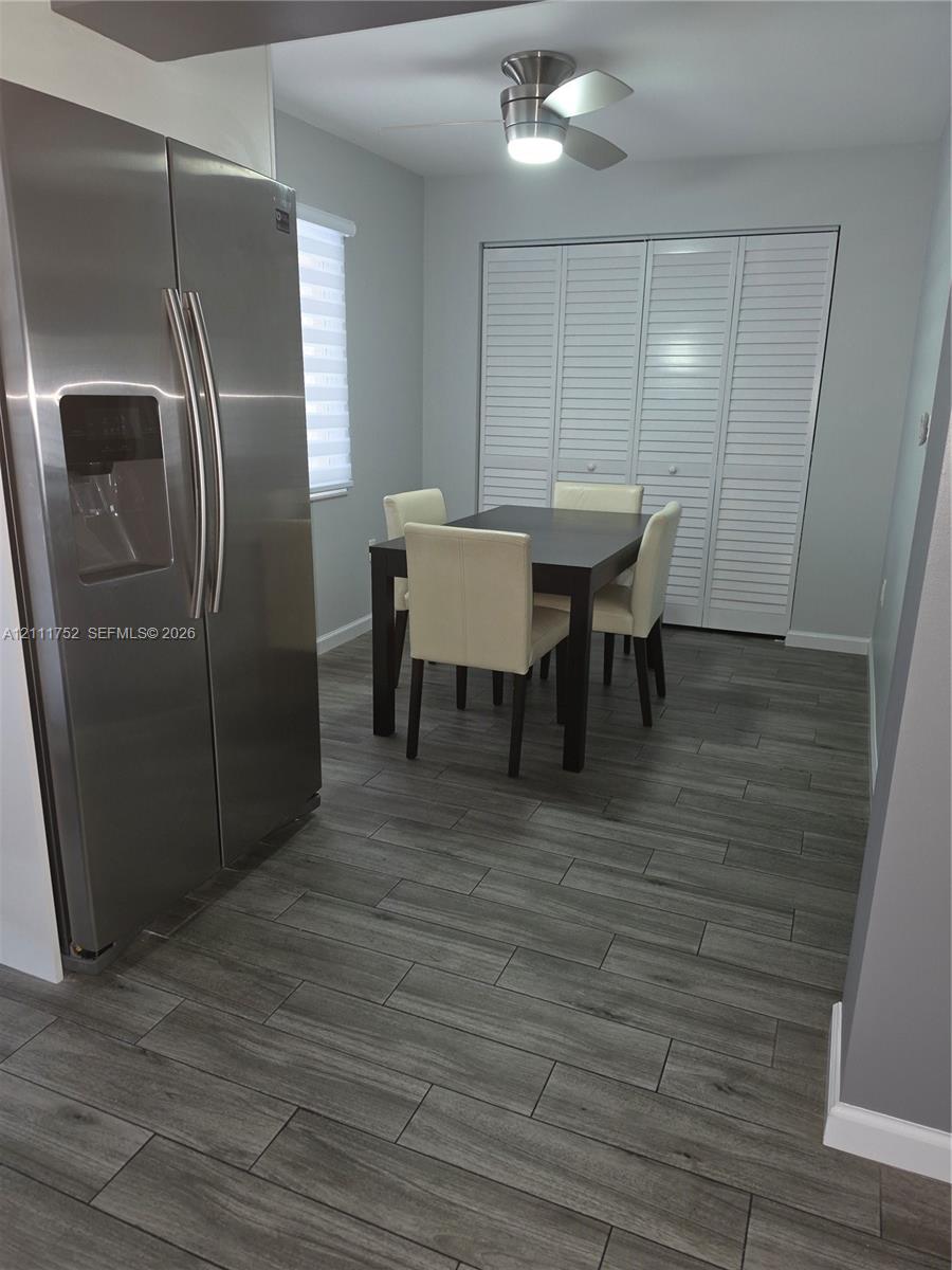 Wood-finish flooring, stainless steel side-by-side refrigerator, ceiling-mounted light fixture, and floor-to-ceiling louvered closet doors