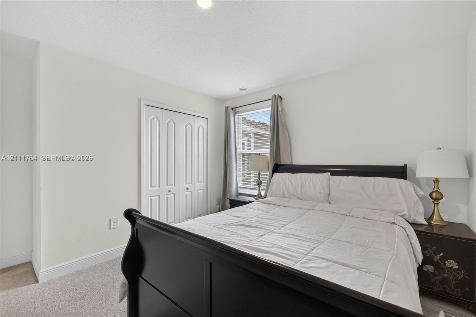 Neutral interior featuring carpeting, a single window, and white bi-fold closet doors