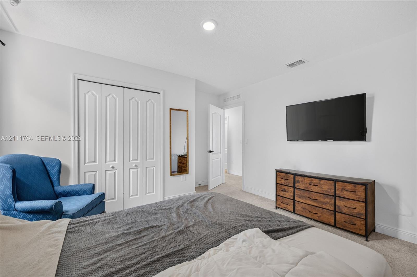 Room featuring neutral wall tones, recessed lighting, carpeted flooring, and a double-door closet with paneled detailing