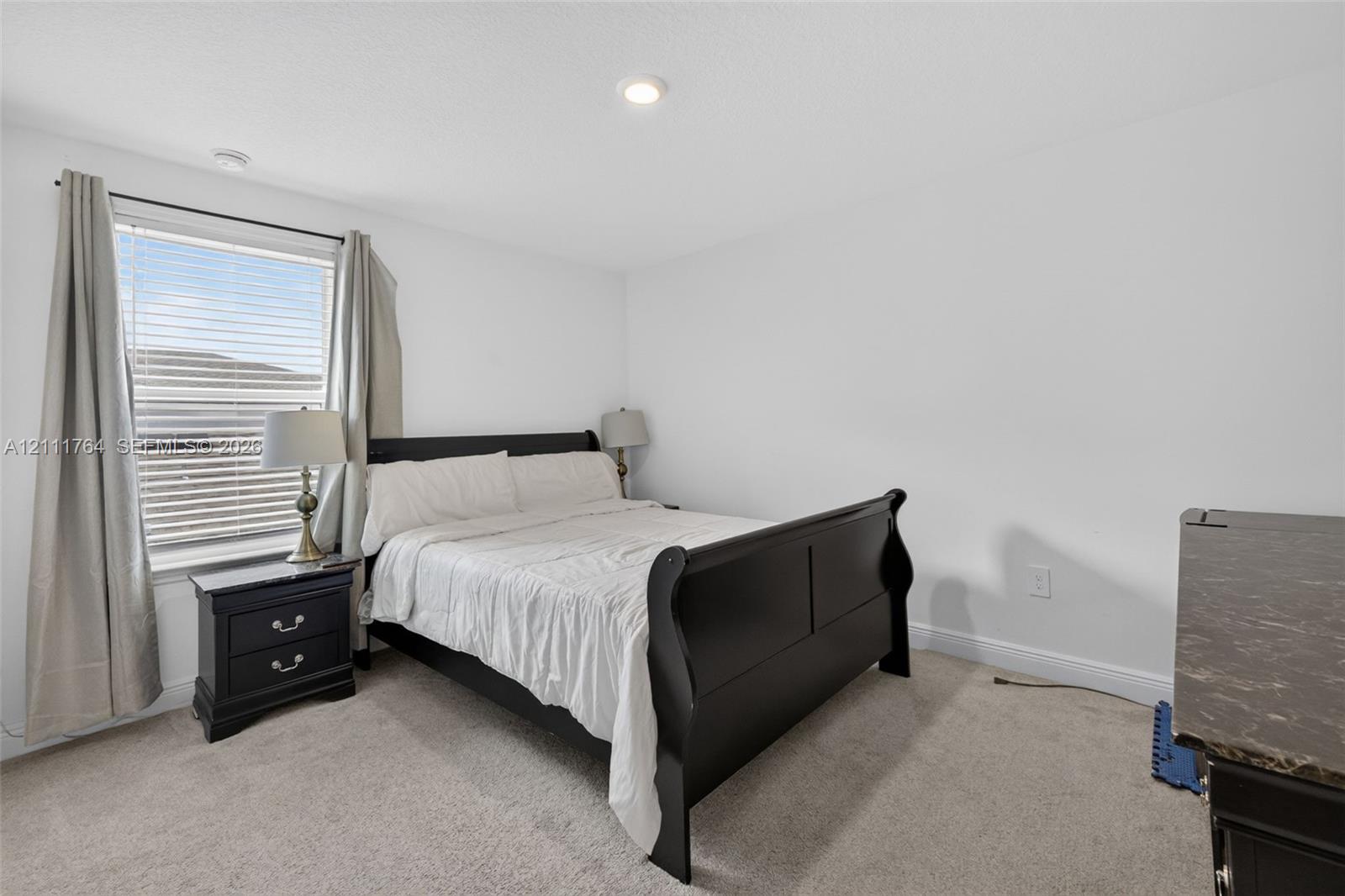 Bedroom featuring neutral wall-to-wall carpeting, recessed ceiling lighting, and a window with horizontal blinds