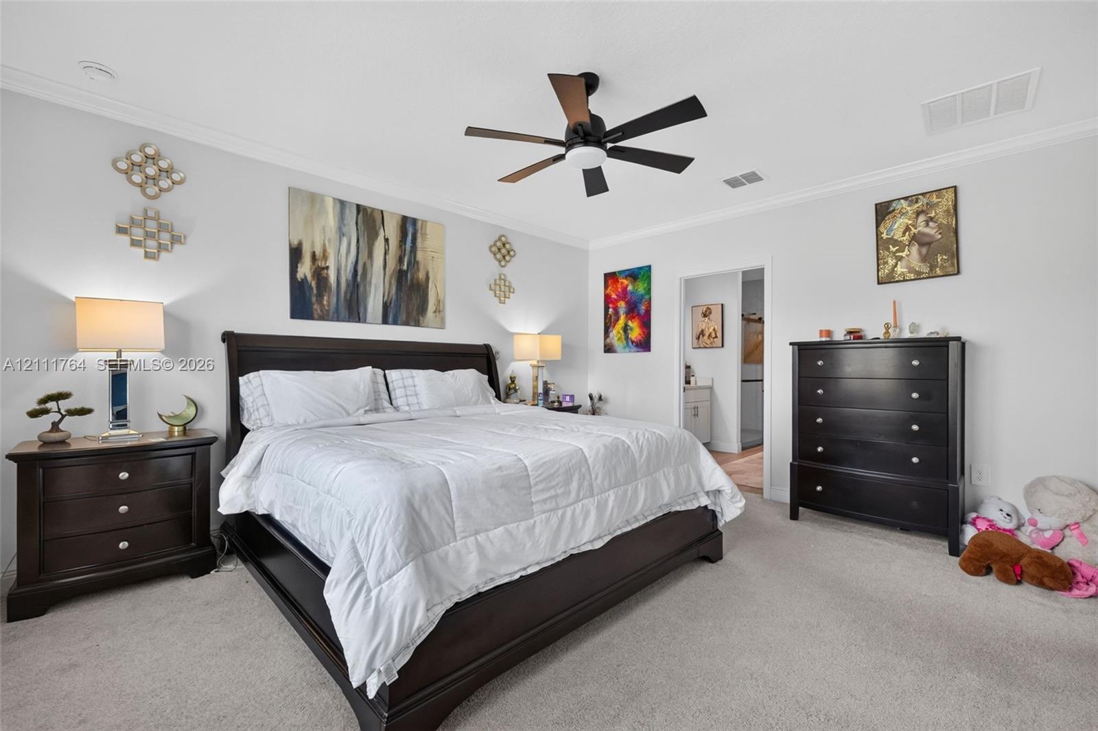 Neutral-toned interior space featuring crown molding, carpeting, and a multi-blade ceiling fan with integrated lighting
