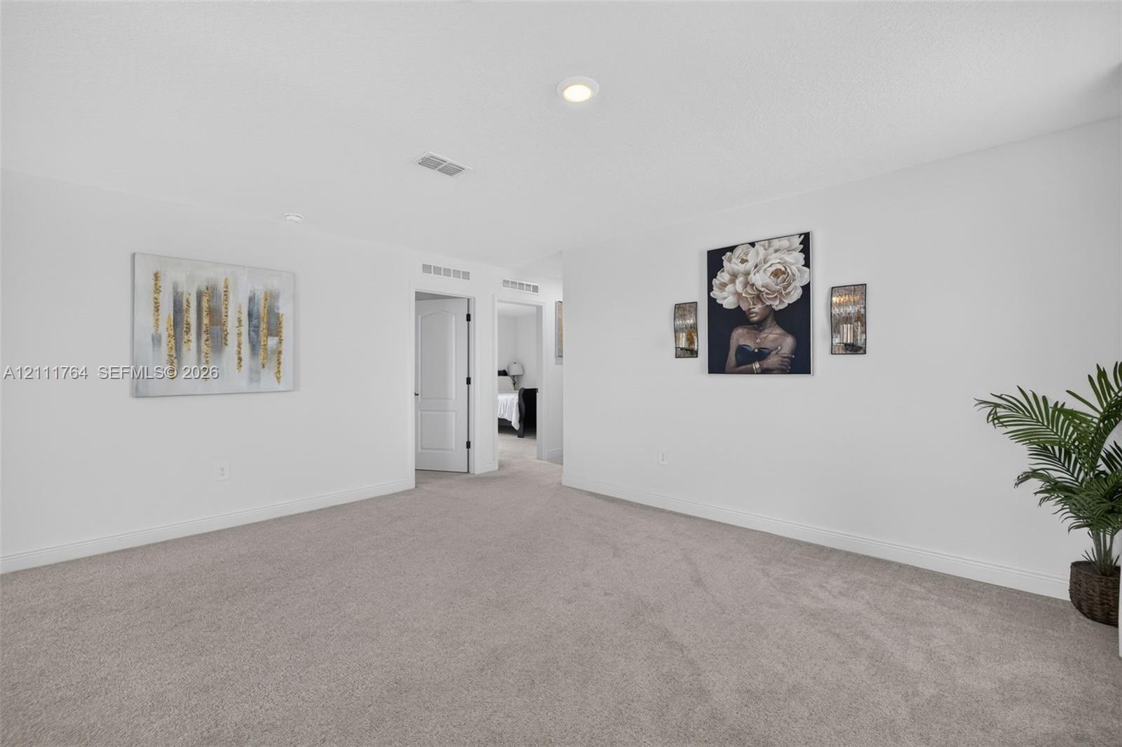 Neutral-toned wall-to-wall carpeting, recessed ceiling lighting, and solid-core interior doors with minimalist hardware