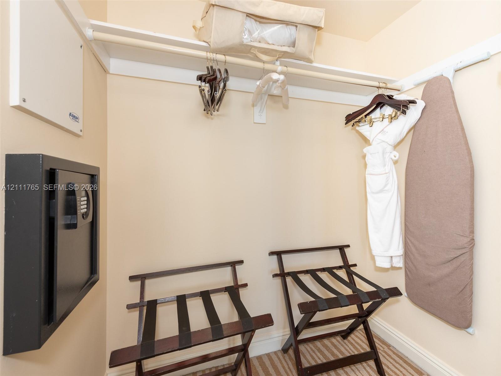 Storage area featuring a wall-mounted electronic safe and integrated upper shelving with a closet rod