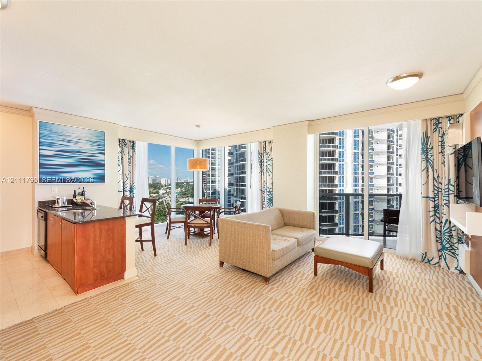 Floor-to-ceiling windows, built-in kitchenette with stone countertops, tiled flooring, and access to a private balcony