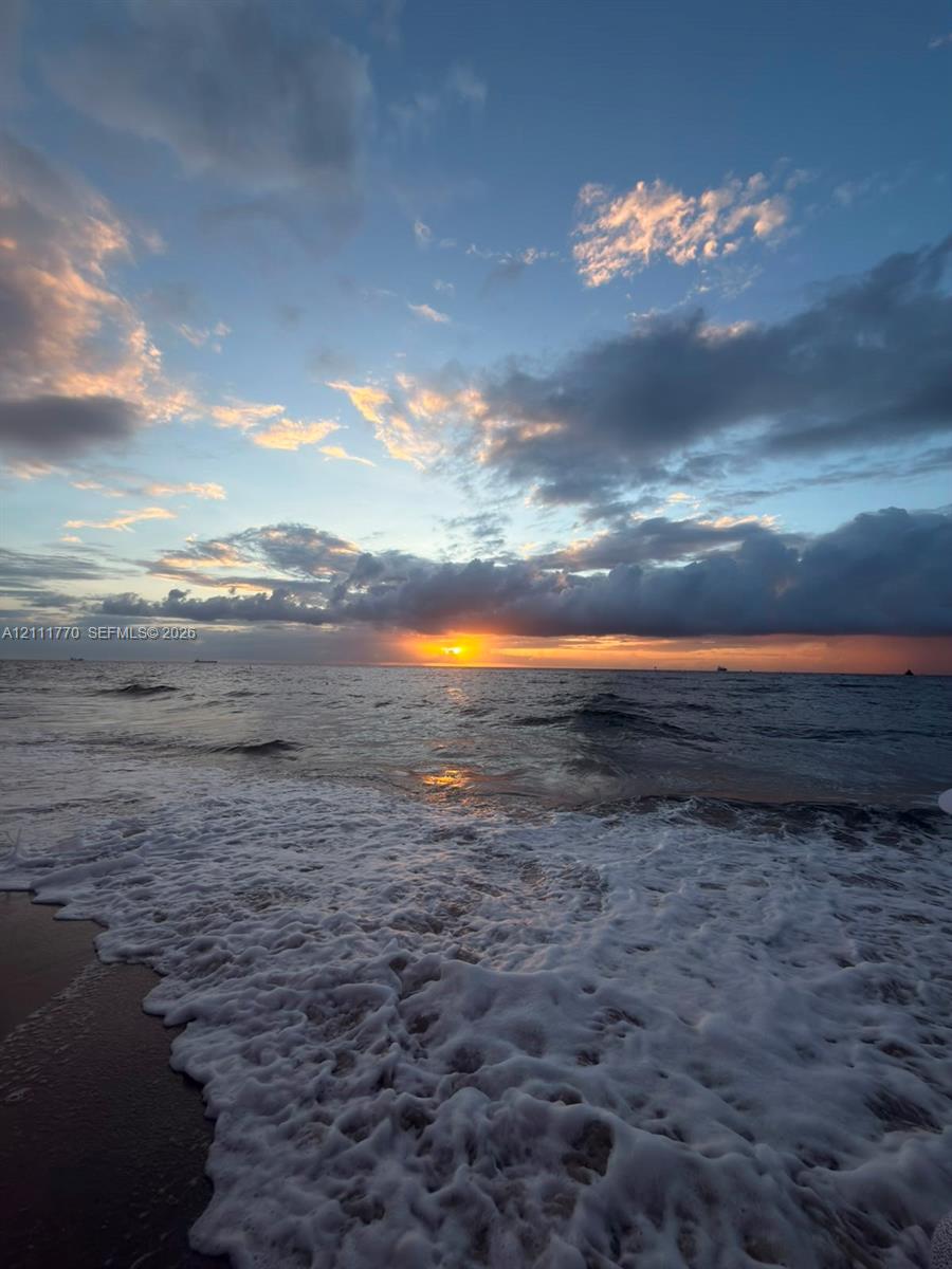 Oceanfront setting featuring direct water access, sandy beach terrain, and a horizon sunset