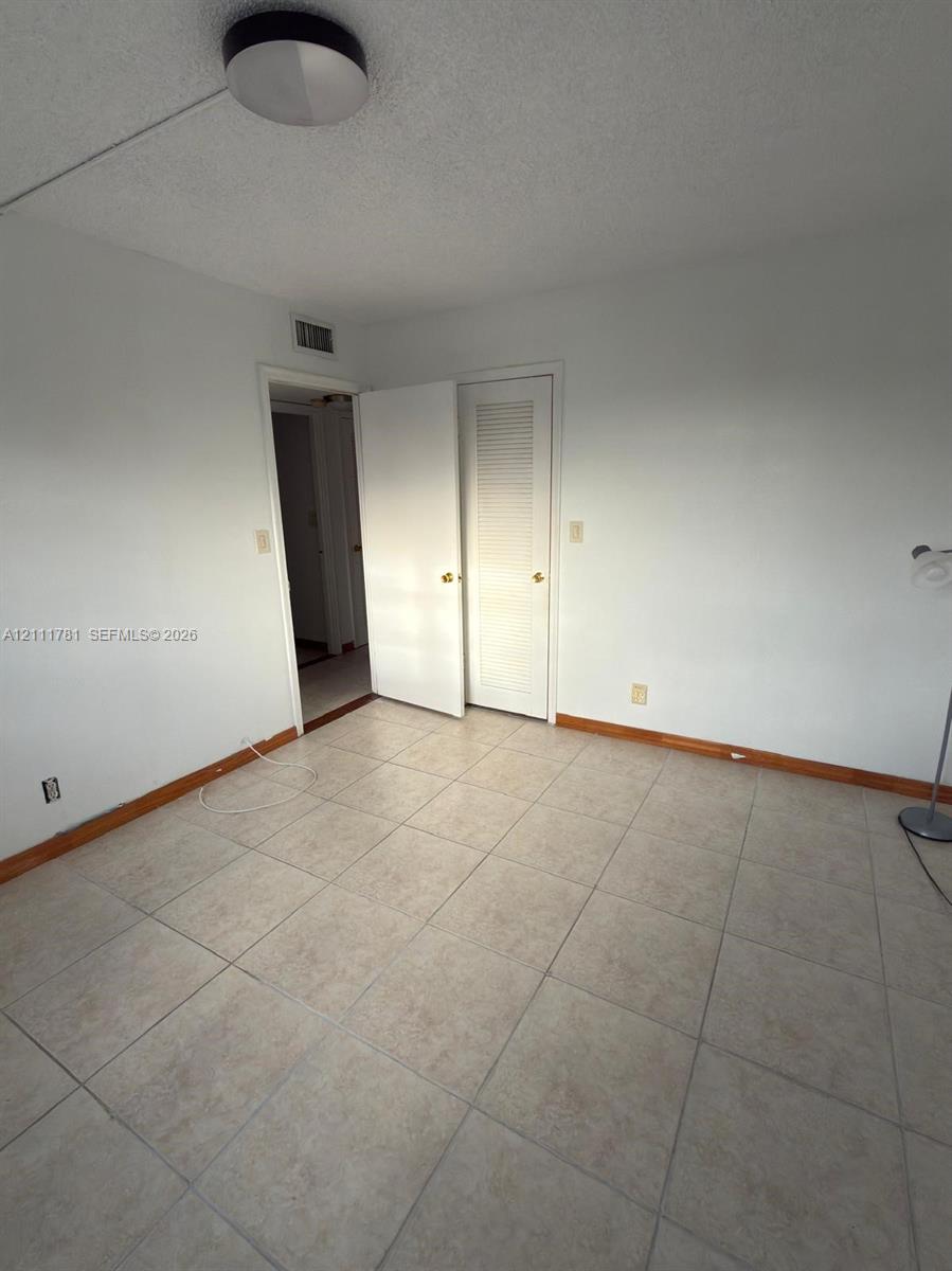 Ceramic tile flooring, neutral wall finishes, and louvered closet door