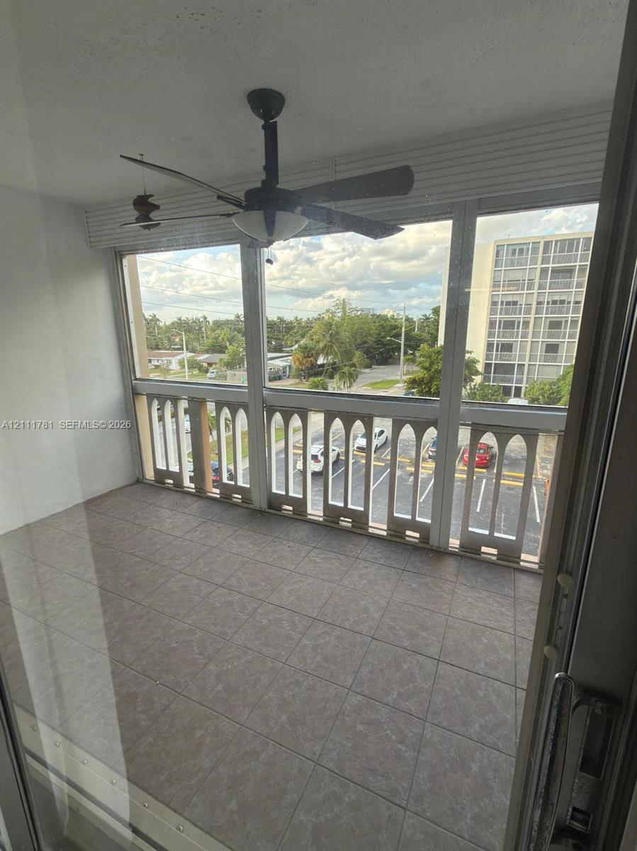Enclosed balcony featuring tile flooring, decorative arched railings, and a ceiling fan