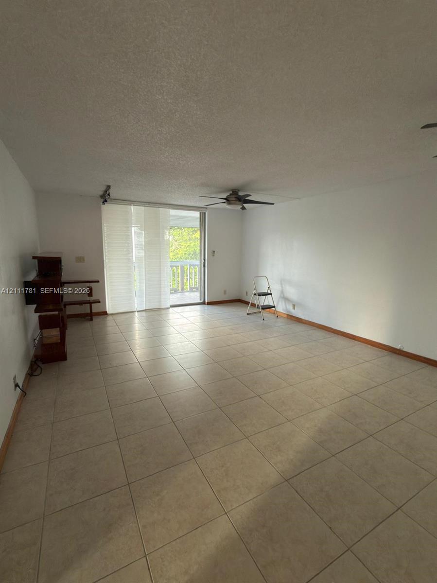 Neutral-toned tile flooring, ceiling fan, and sliding glass door leading to an outdoor balcony
