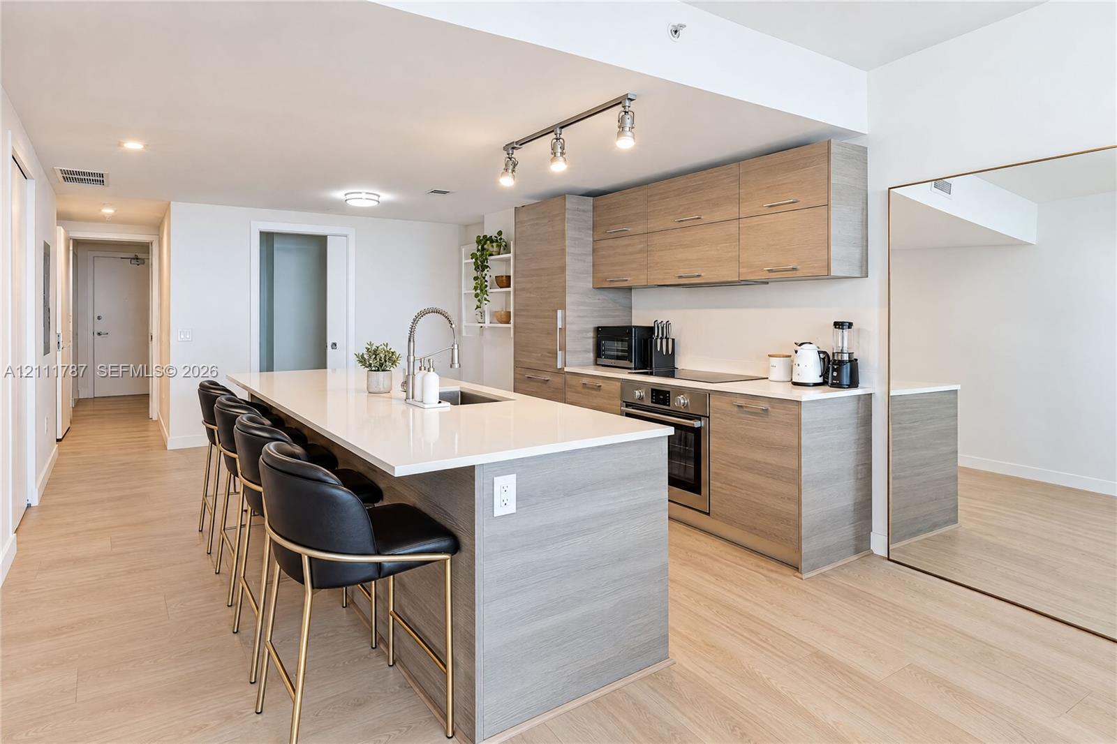 Kitchen featuring wood-finish cabinetry, quartz countertops, a kitchen island, stainless steel appliances, and wood-finish flooring