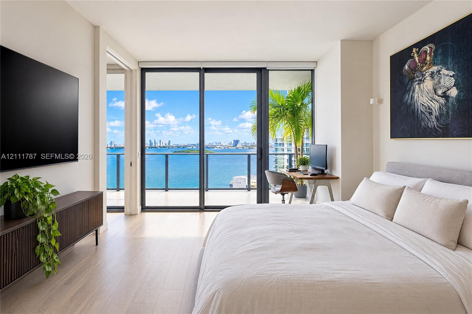 Light-toned wood-finish flooring, floor-to-ceiling sliding glass doors, and a private balcony featuring a metal railing