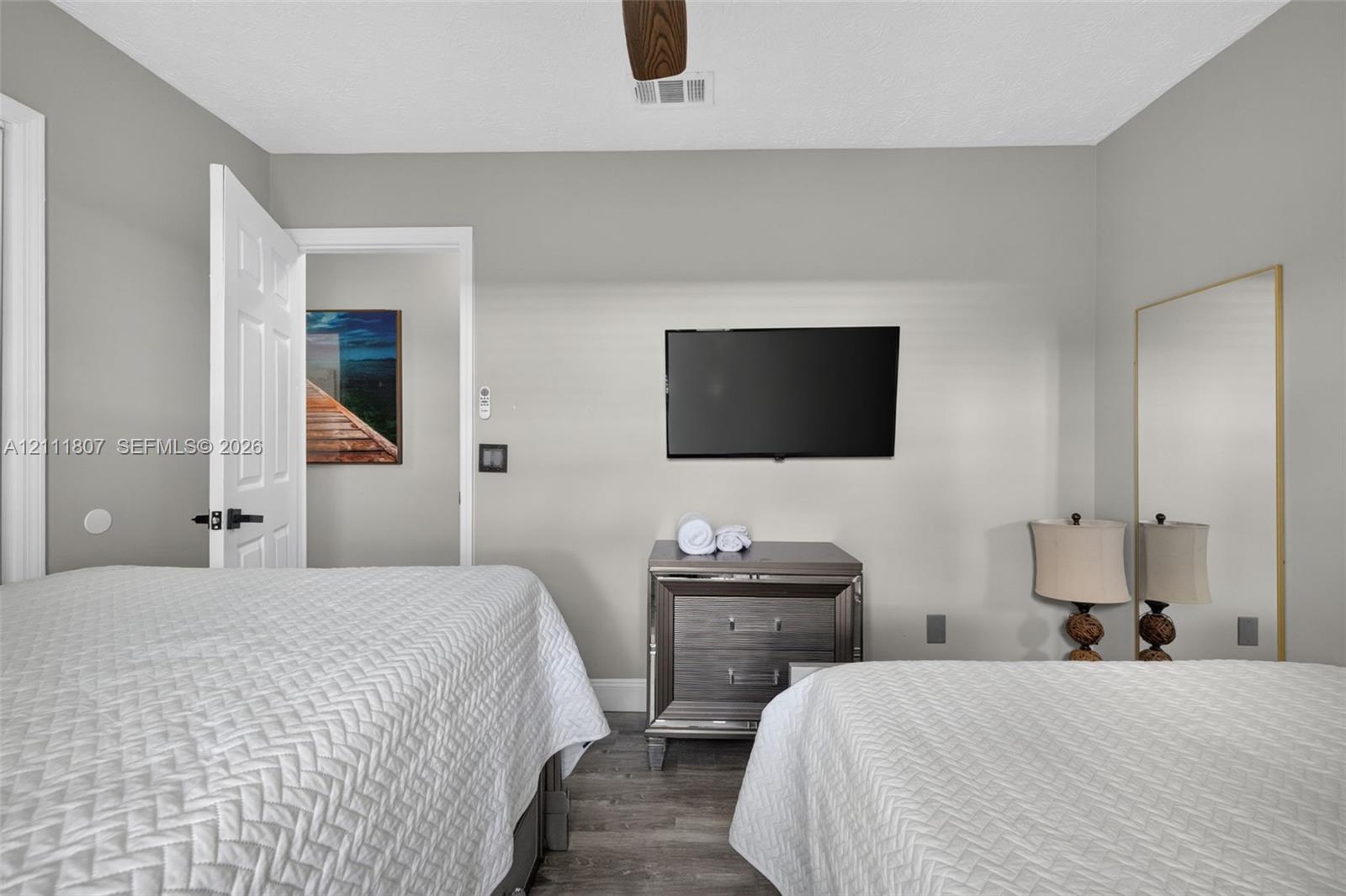 Room featuring neutral walls, wood-finish flooring, and a ceiling fan with integrated lighting