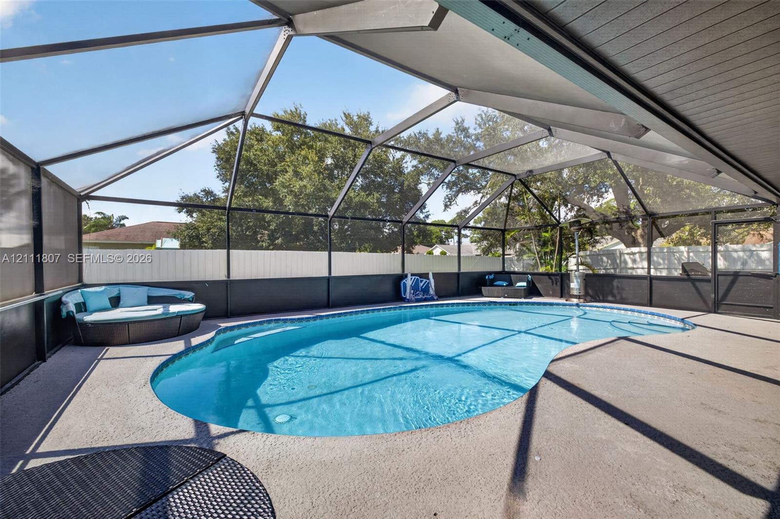Screened-in enclosure featuring a free-form swimming pool and aggregate concrete patio surfacing