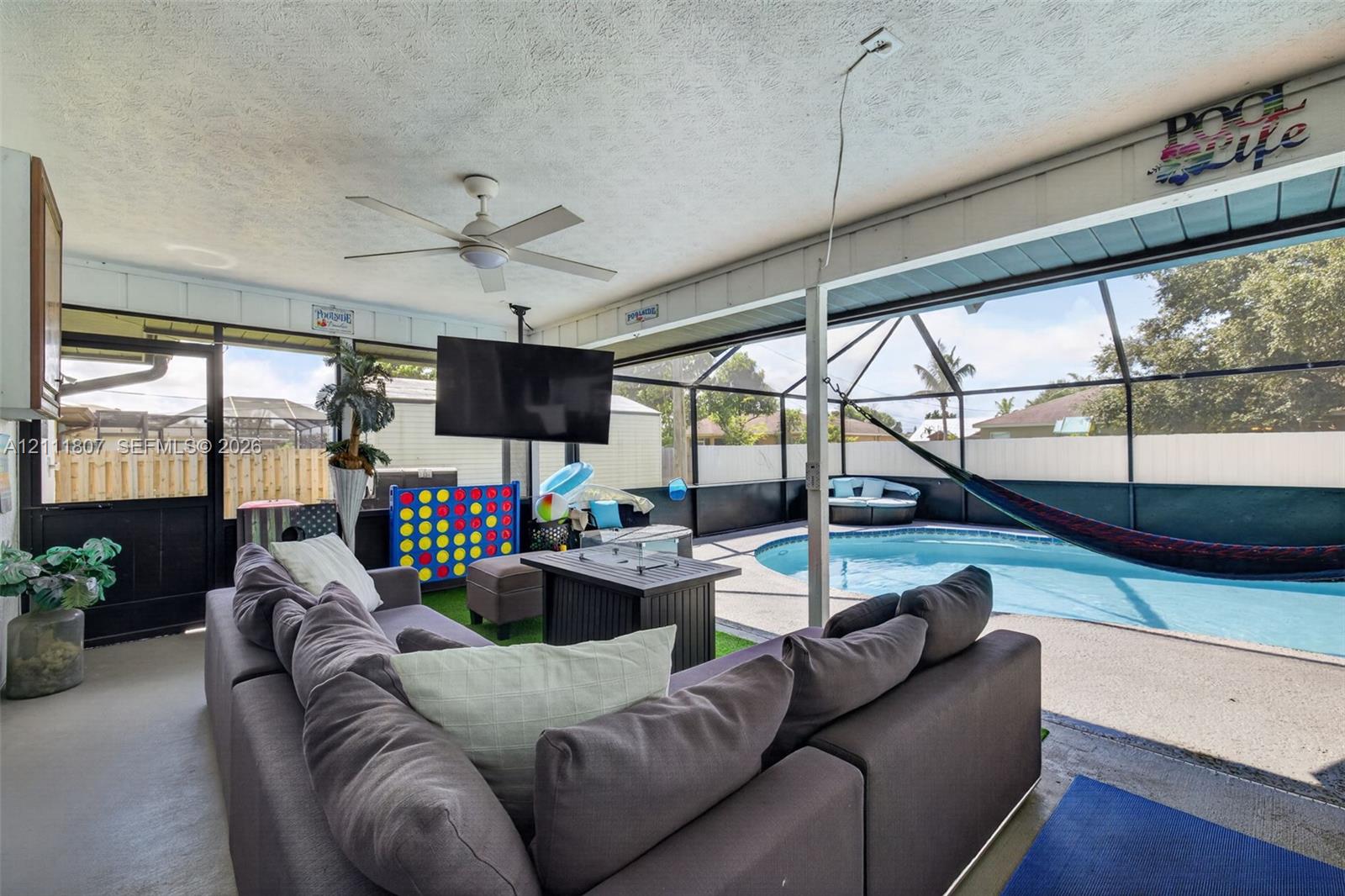 Screened-in lanai featuring a concrete patio, built-in ceiling fan, and in-ground swimming pool