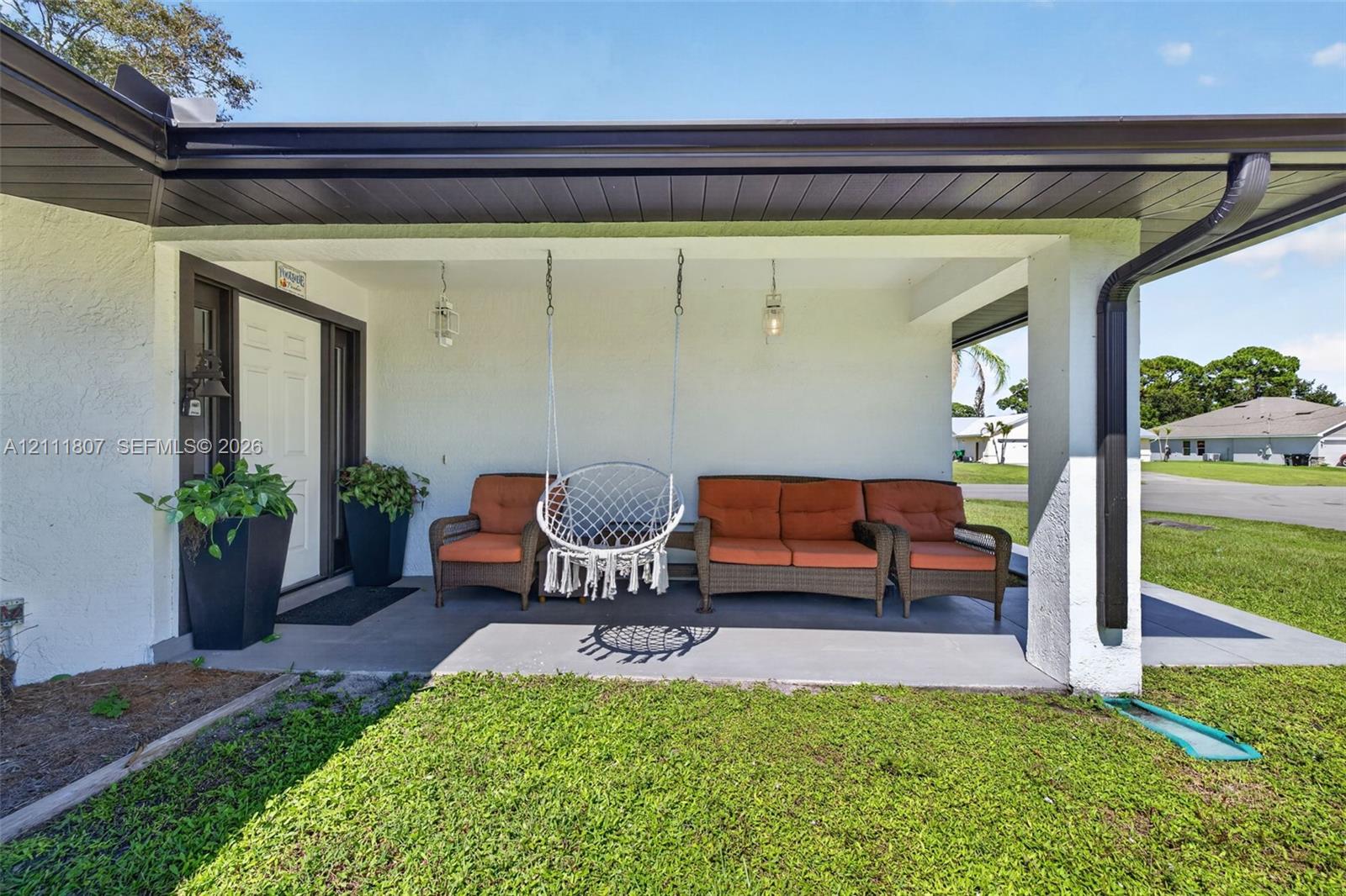 Covered front porch featuring smooth concrete flooring, dark trim, integrated ceiling lighting, and a paneled entry door Covered front porch featuring smooth concrete flooring, dark trim, integrated ceiling lighting, and a paneled entry door