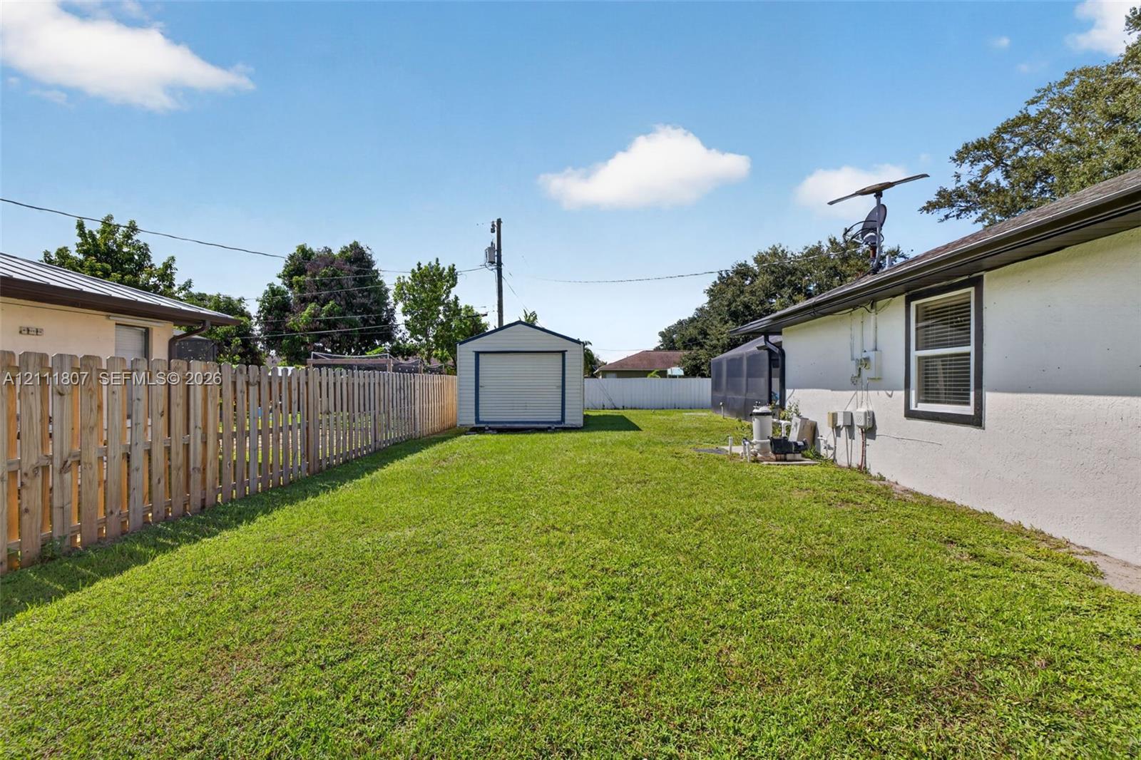 Backyard featuring a grass lawn, perimeter wood fence, and a detached storage shed
