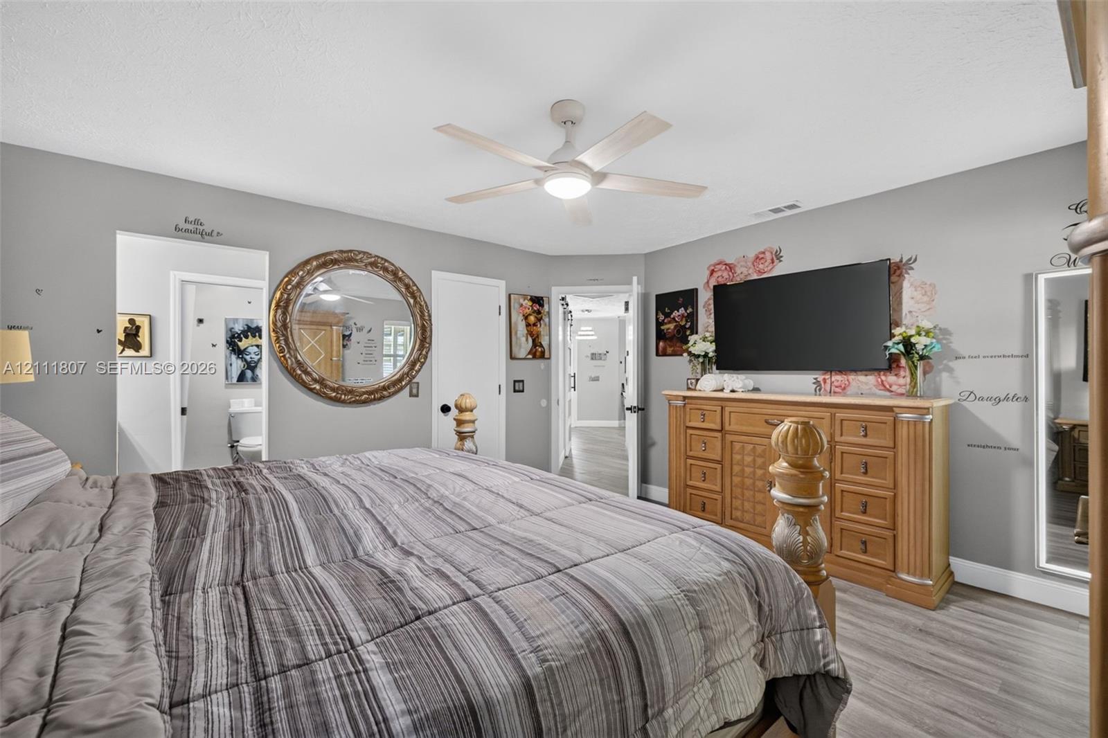 Neutral-toned interior featuring wood-finish flooring and a central ceiling fan with an integrated light fixture
