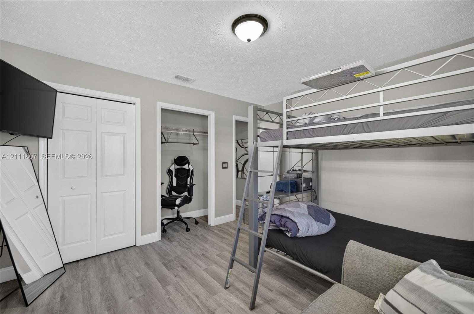 Neutral-toned interior featuring wood-finish flooring, a double-door closet, and a ceiling-mounted light fixture
