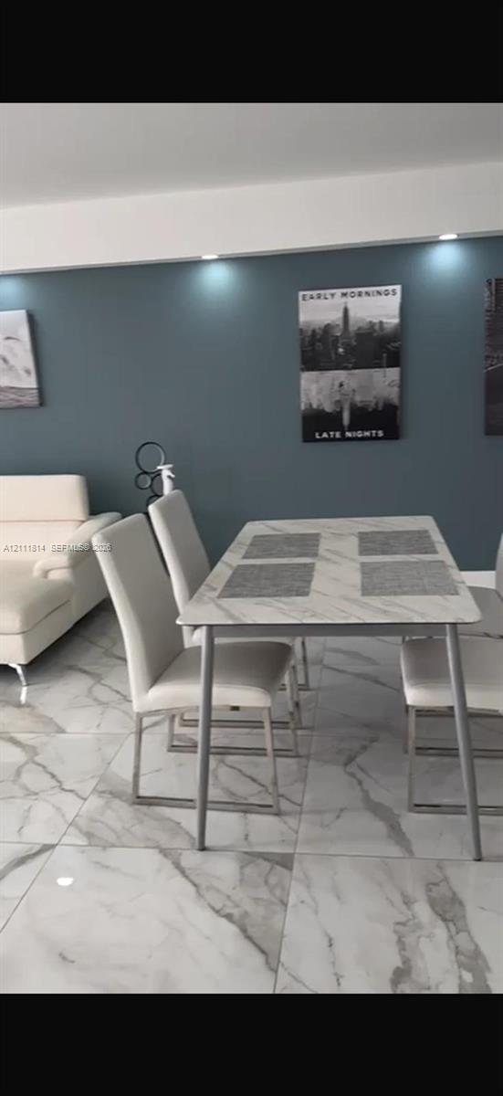 Large-format tile flooring with a neutral-toned veined pattern, accent wall featuring recessed ceiling lighting, and crisp white trim